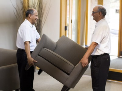 Two men moving a couch in a living room.