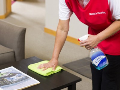 A person cleaning the table with a spray bottle