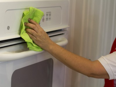 A person cleaning an oven with green cloth.