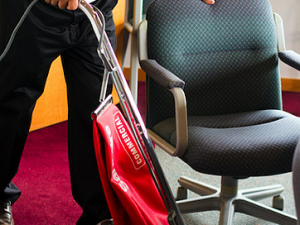 A person holding a red bag in front of an office chair.